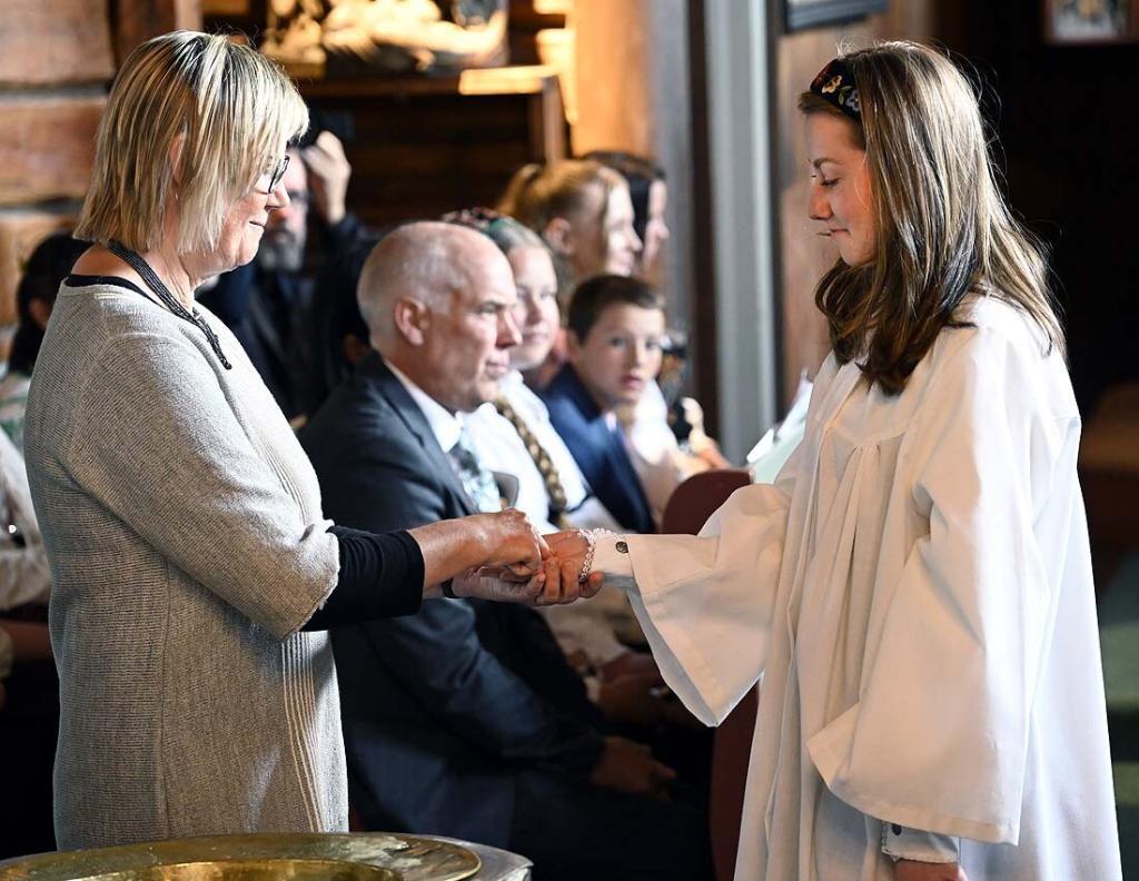 Klokker Kirsten Greaker Heimestøl minner Malin på dåpen, og gir henne korsets tegn i hånden. Foto: Arne G. Perlestenbakken