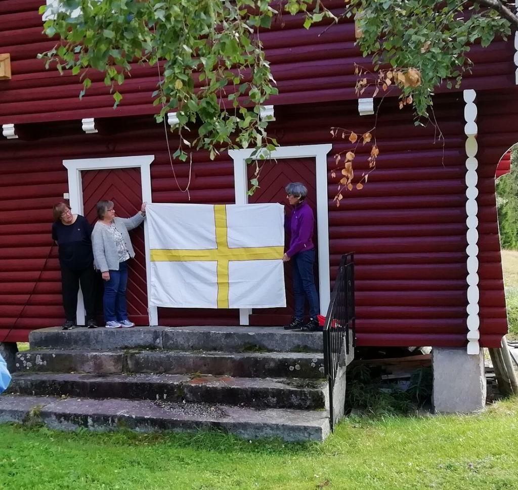 Her viser søstrene Goplerud fram Olavsflagget da Sør-Aurdal Historielag hadde tur til Goplerud og Vatneberget i 2020. Foto: Sigrid Haugen